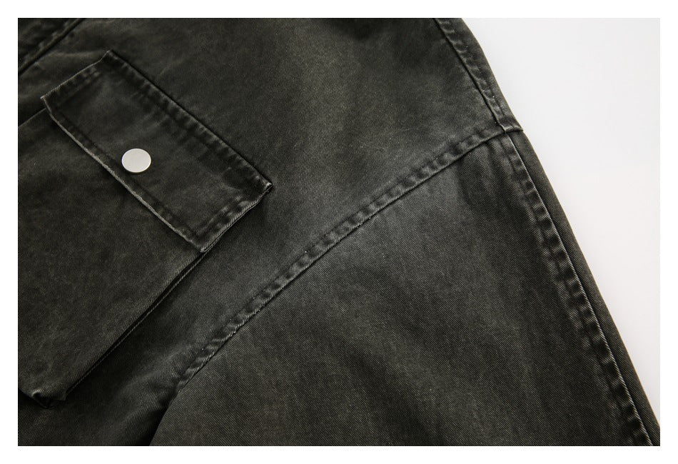 Close-up of a dark washed jacket sleeve with a snap-fastened cuff tab and visible seam.