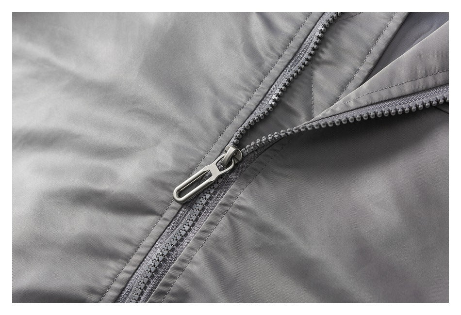 Close-up of a gray garment zipper with a metal pull and stitched seam.