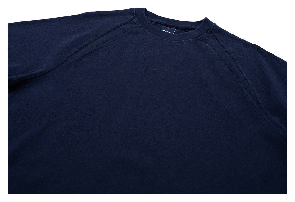 Close-up of a navy raglan crew-neck shirt, showing the front chest, neckline, and upper sleeves.