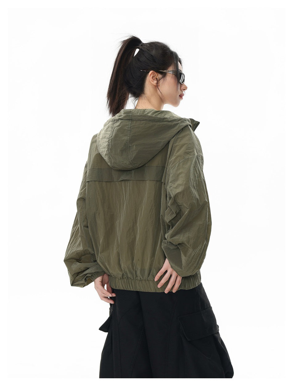 Model wearing an olive hooded jacket, shown from behind at an angle with the hood down.