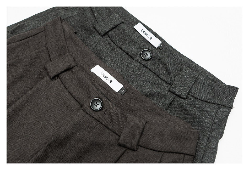 Two pairs of trousers in charcoal and dark brown, shown at the waist with buttons and belt loops.