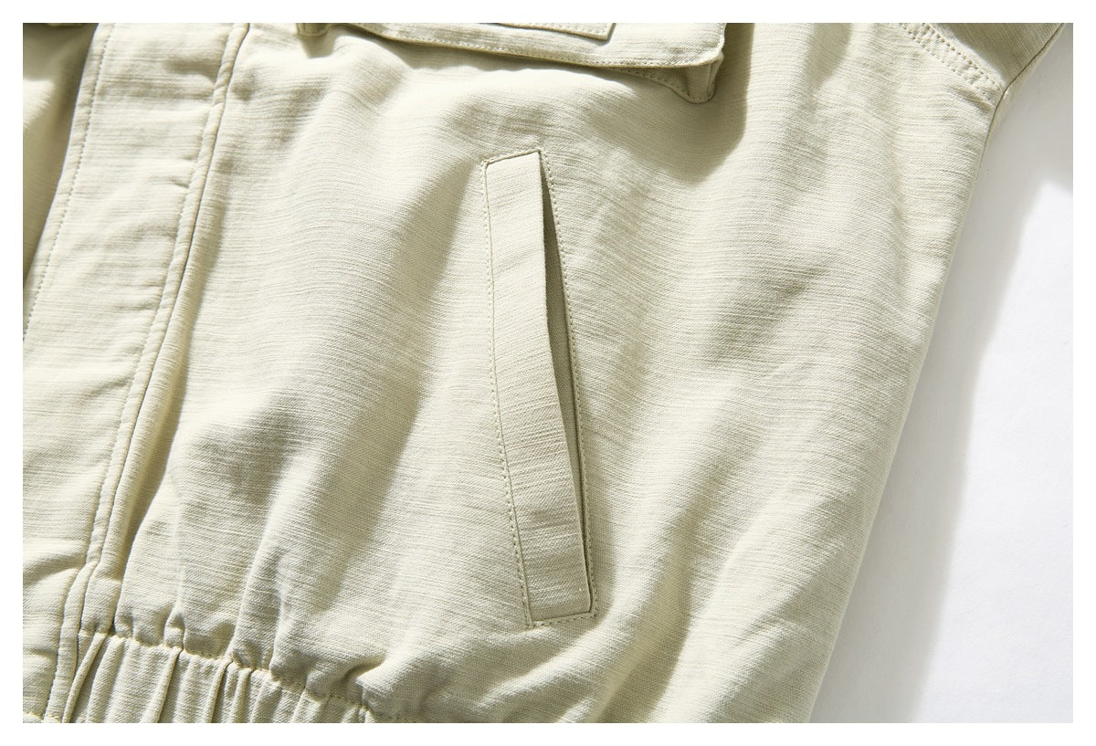 Close-up of an ivory jacket's slanted side pocket opening and gathered lower seam.