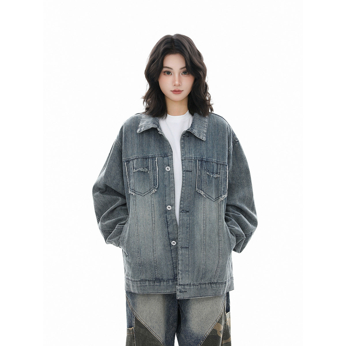 Model wearing an oversized blue-gray denim jacket with a button front and distressed chest pockets.