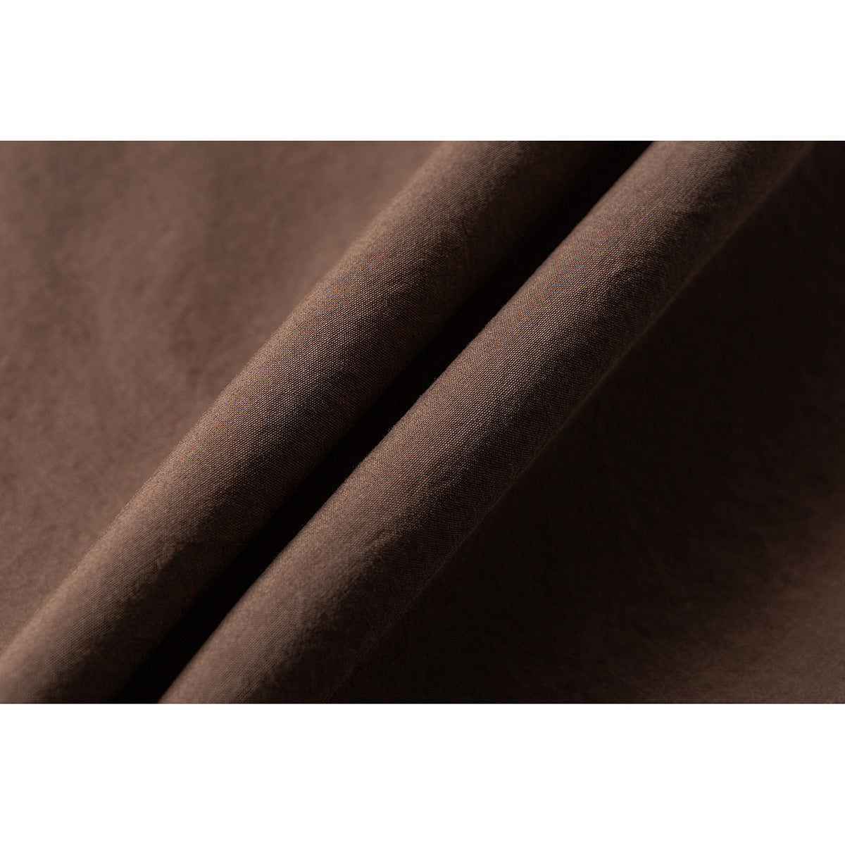 Macro view of brown fabric draped in folds, showing its surface and weave.