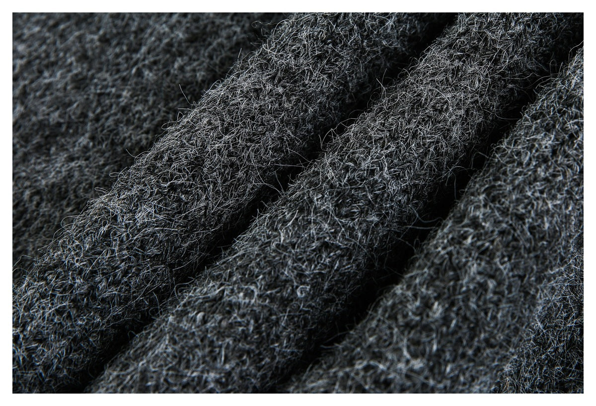 Close-up of dark charcoal gray fuzzy knit fabric gathered into soft folds.