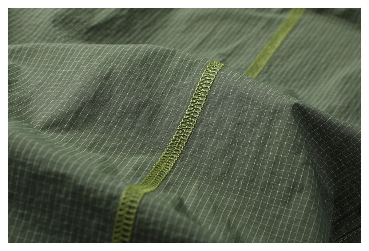 Close-up of lime overlock stitching along olive-green fabric with a fine grid pattern.