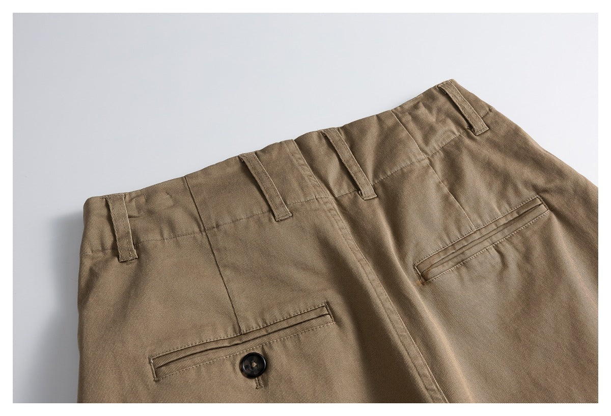 Close-up of the brown trousers' waistband, belt loops and buttoned welt pockets.