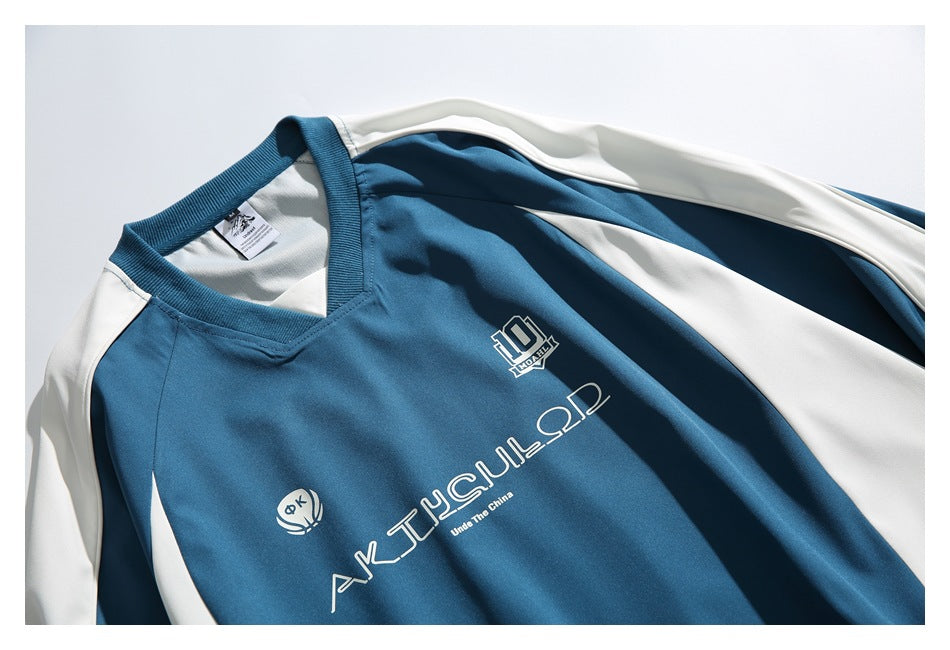 Close-up of the blue pullover's front, showing its V-neck, white shoulder panels, and printed chest graphics.