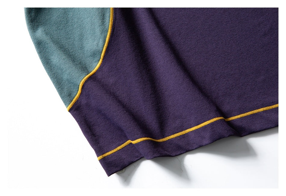 Close-up of a purple hem with a teal panel and mustard-yellow stitching.