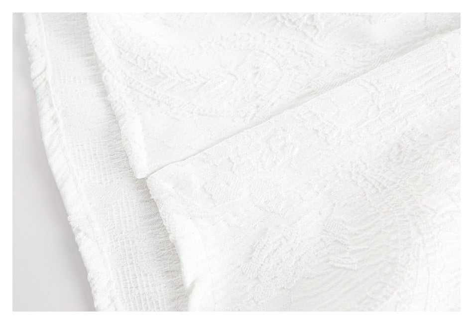 Close-up of layered white garment edges with raised floral and geometric fabric texture.