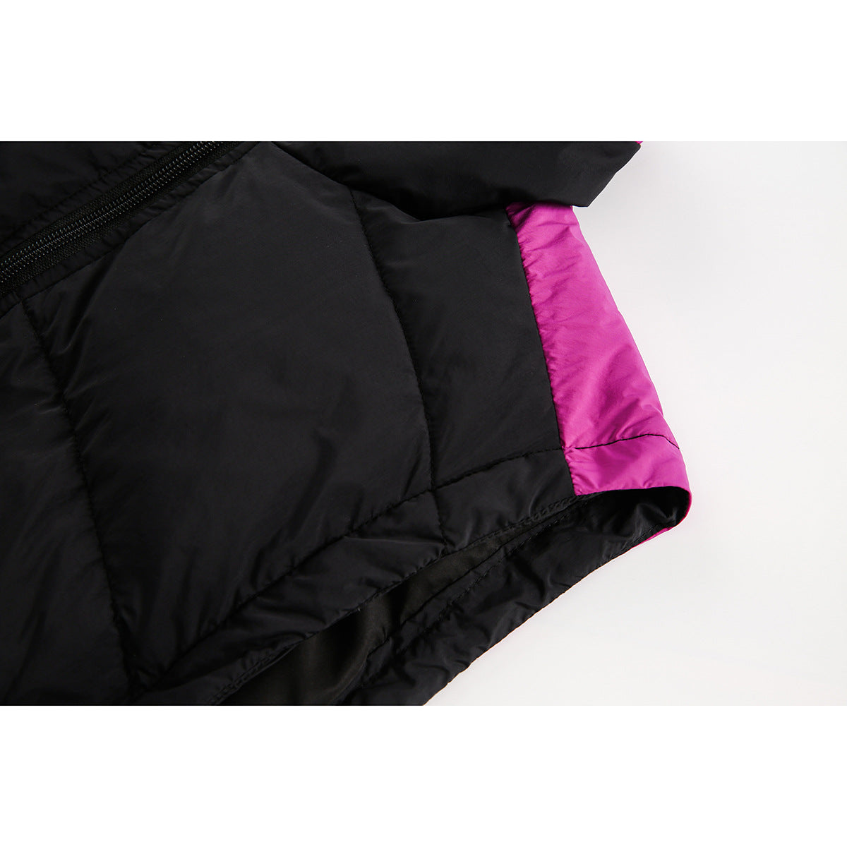 Close-up of a black quilted jacket hem with a bright magenta side panel and visible inner lining.