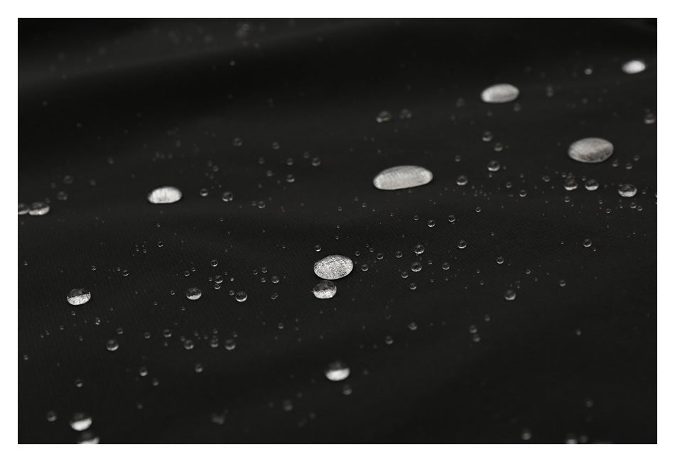 Close-up of black fabric covered with scattered round water droplets.