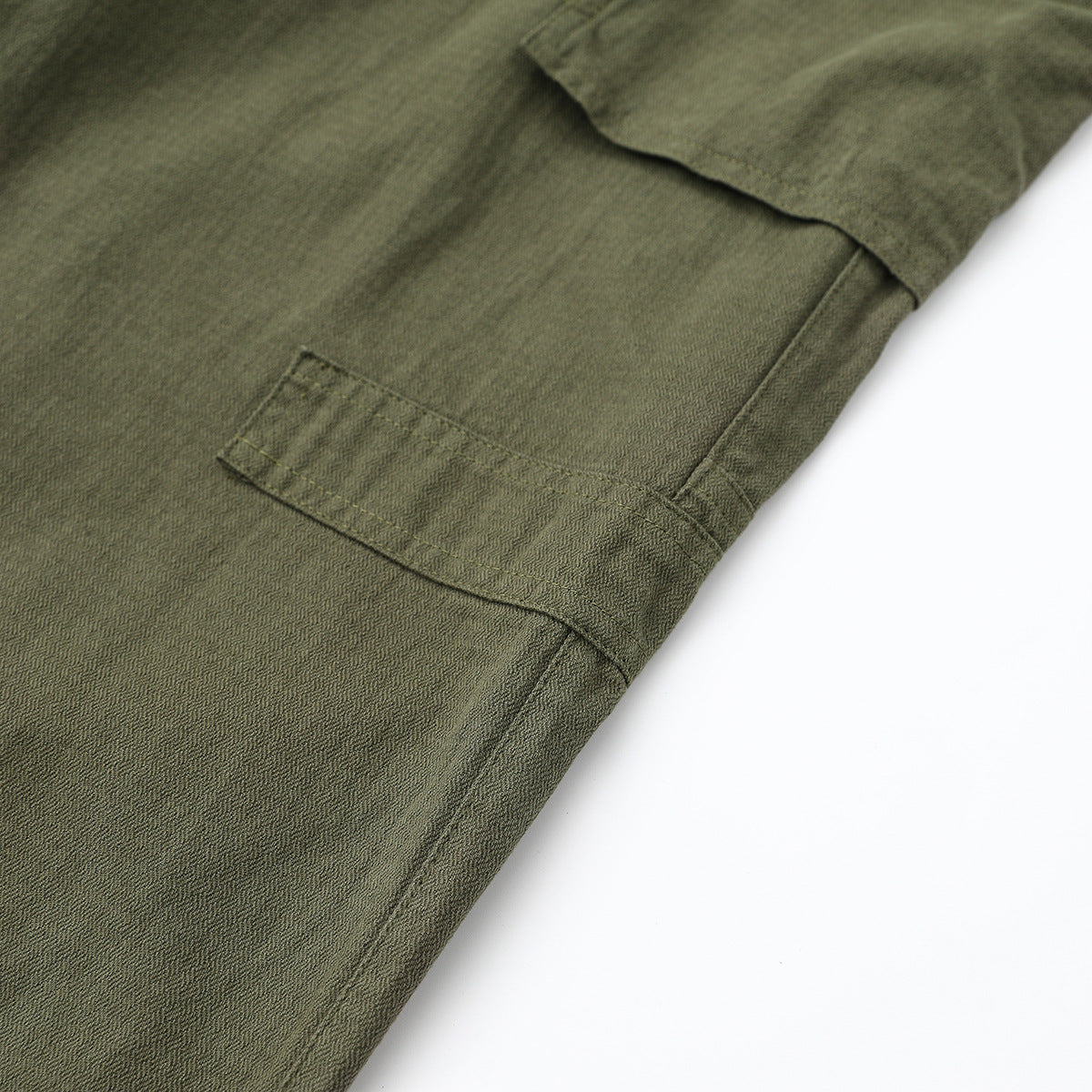 Close-up of olive-gray cargo pants showing a flap pocket and reinforced stitching.