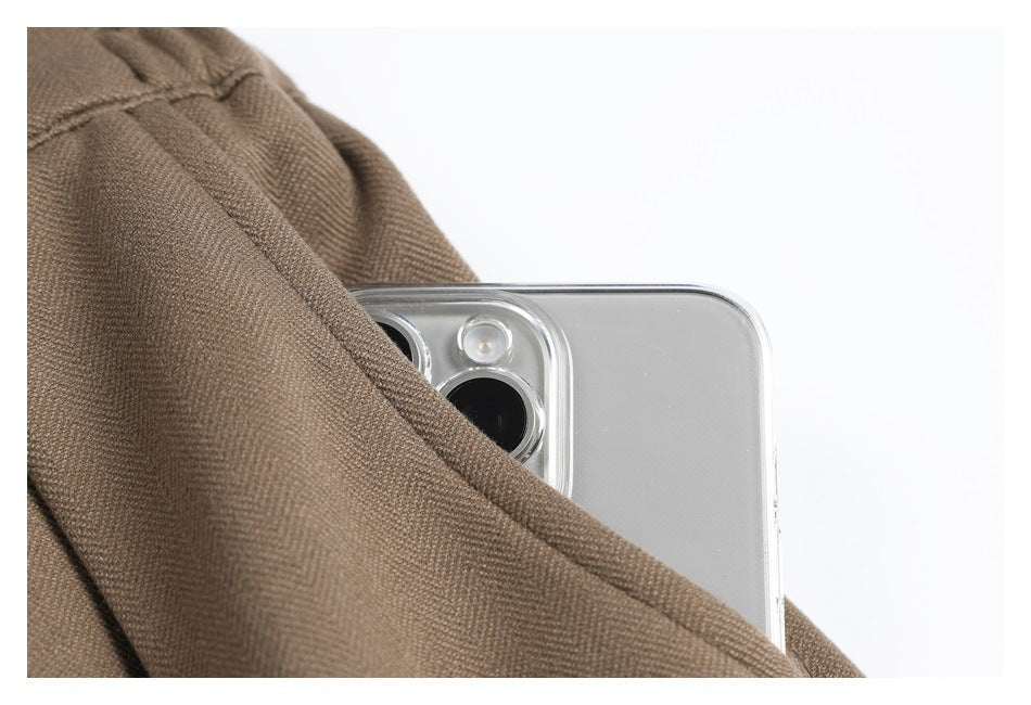 A phone is partly tucked into the pocket of taupe trousers, showing the pocket opening.