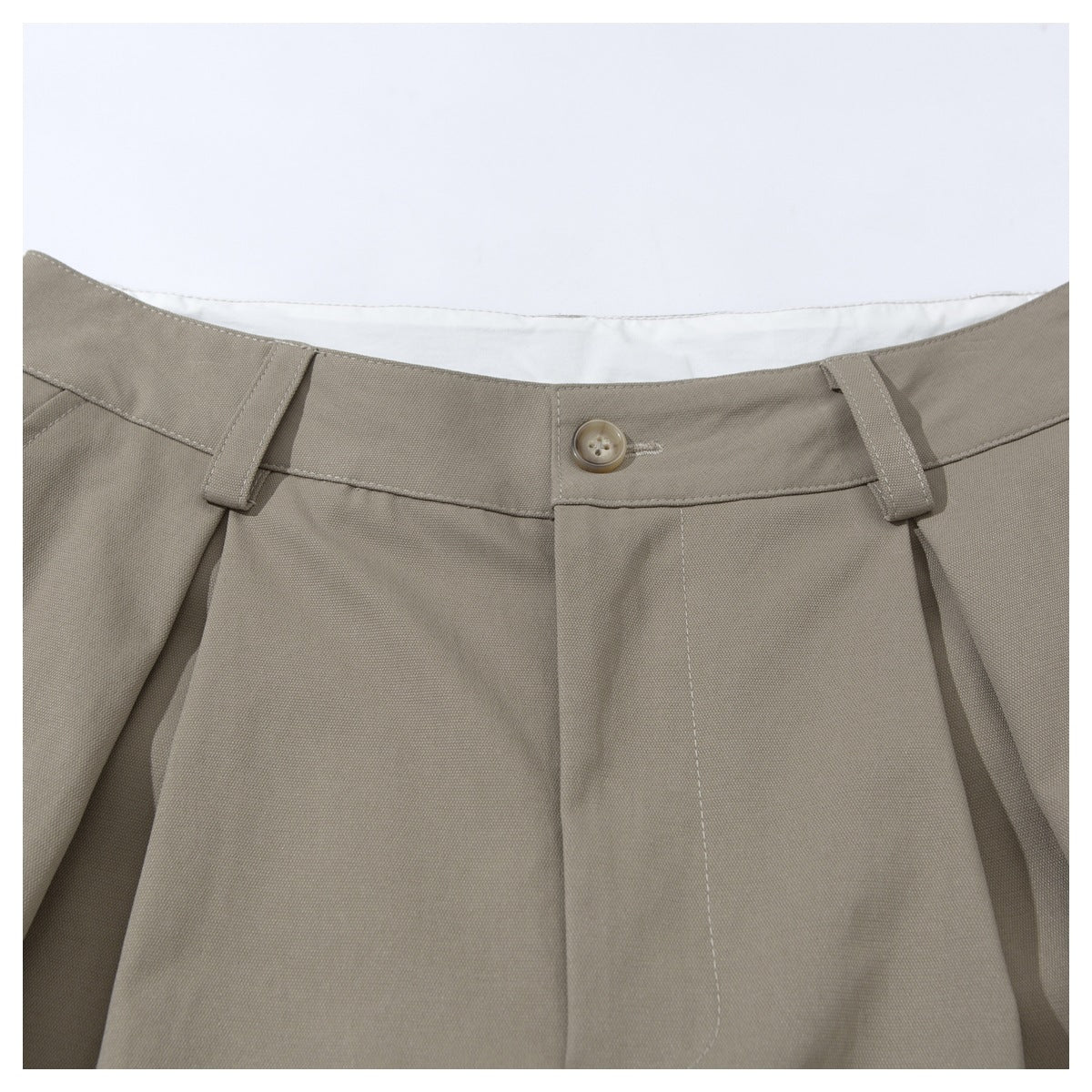 Close-up of taupe tailored shorts showing the front waistband, button, belt loops, and pleats.