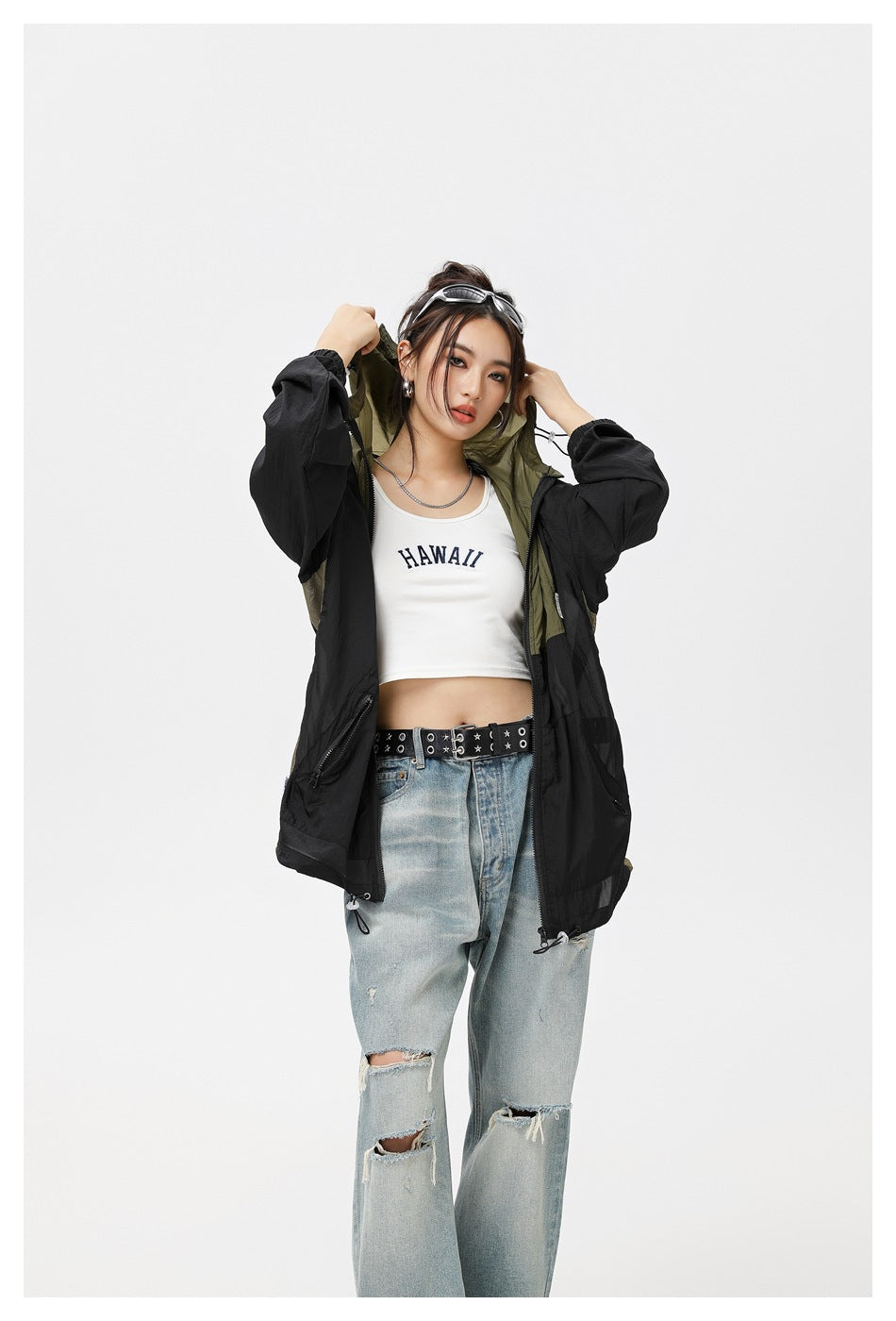 Closer view of a model wearing an open black jacket with olive hood lining and panels.