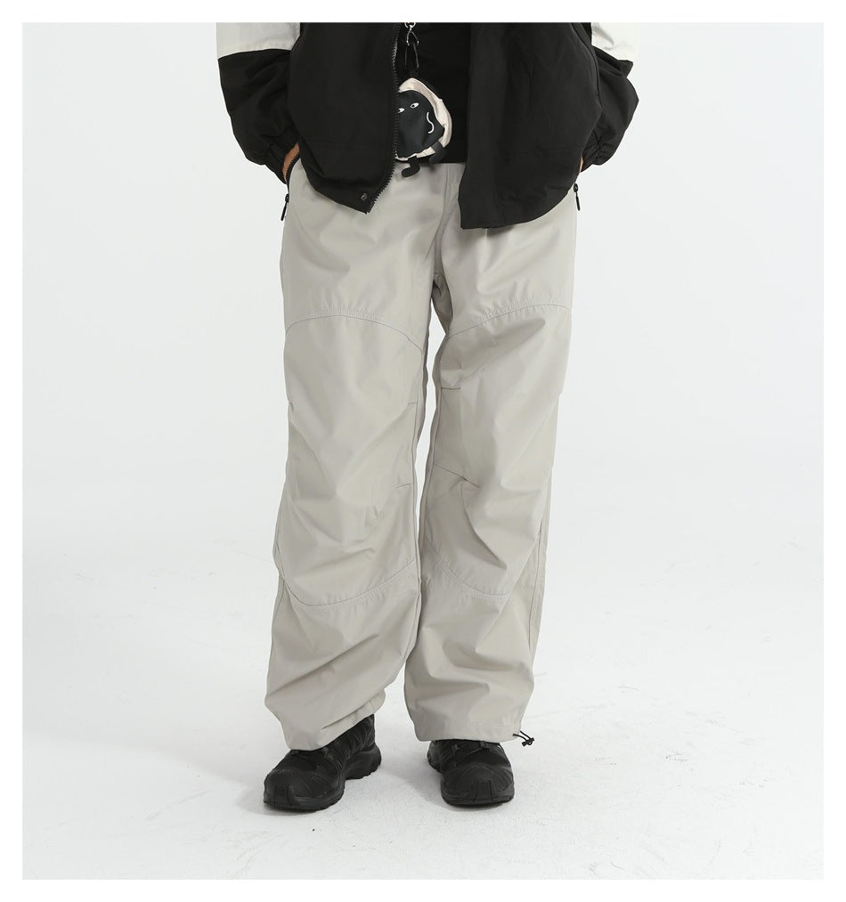 Model wearing light gray loose straight-leg pants with black sneakers and a black and white jacket, front view
