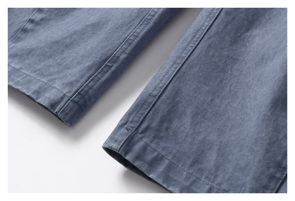 Close-up of blue-gray trouser hems with visible stitching and a softly washed finish.