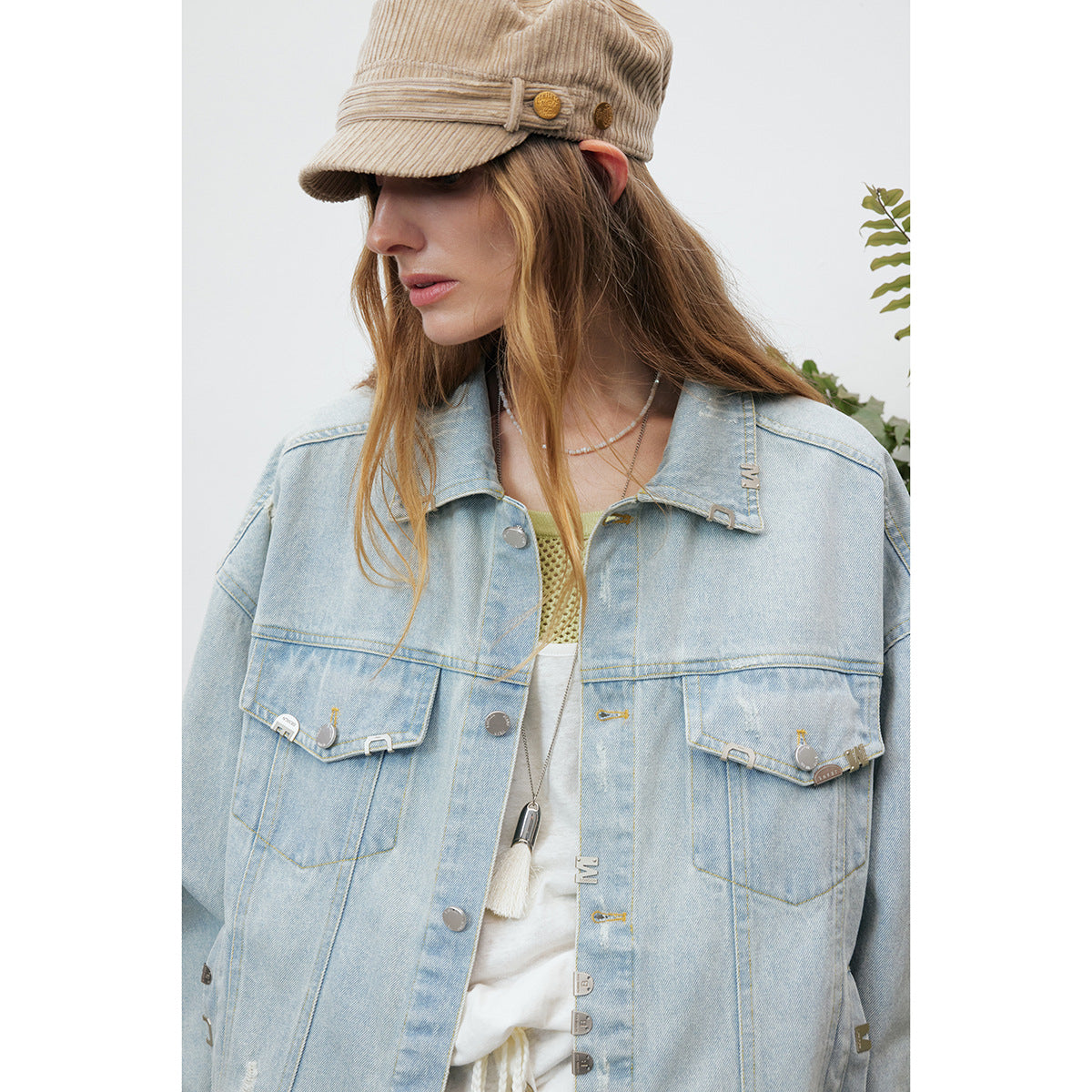 Close-up of a model wearing a light-wash denim jacket with flap chest pockets and metal hardware.