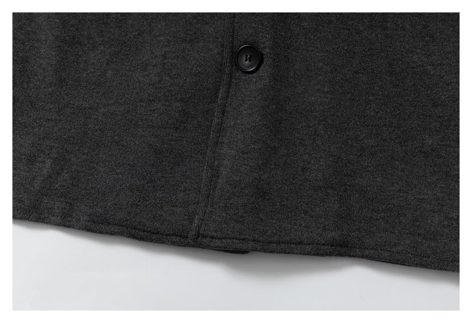 Close-up of a black button and stitched front seam near the hem of a charcoal garment.