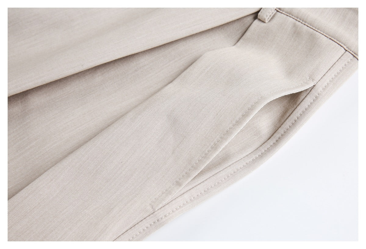 Close-up of beige trousers showing a slanted front pocket, stitching, and fabric texture.
