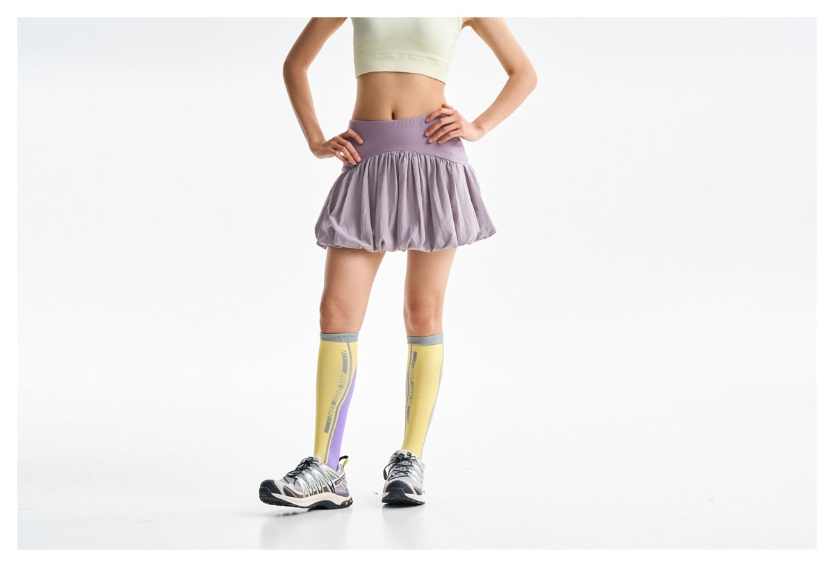Cropped front view of a model wearing a lilac bubble-hem skirt and pale yellow crop tank.
