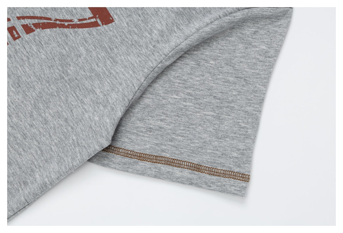 Close-up of a gray heather T-shirt sleeve and brown contrast stitching, with part of a red graphic visible.