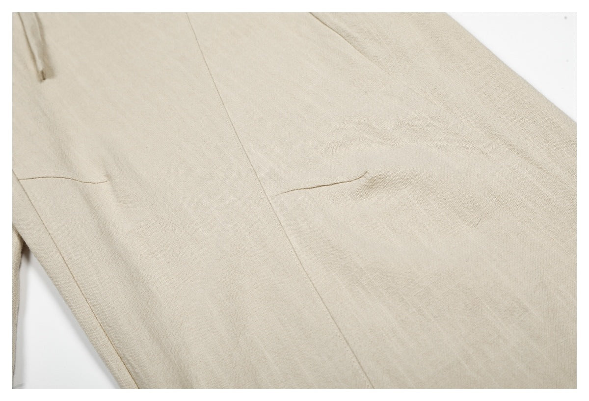 Close-up of beige trousers showing a stitched pocket opening and leg seam.