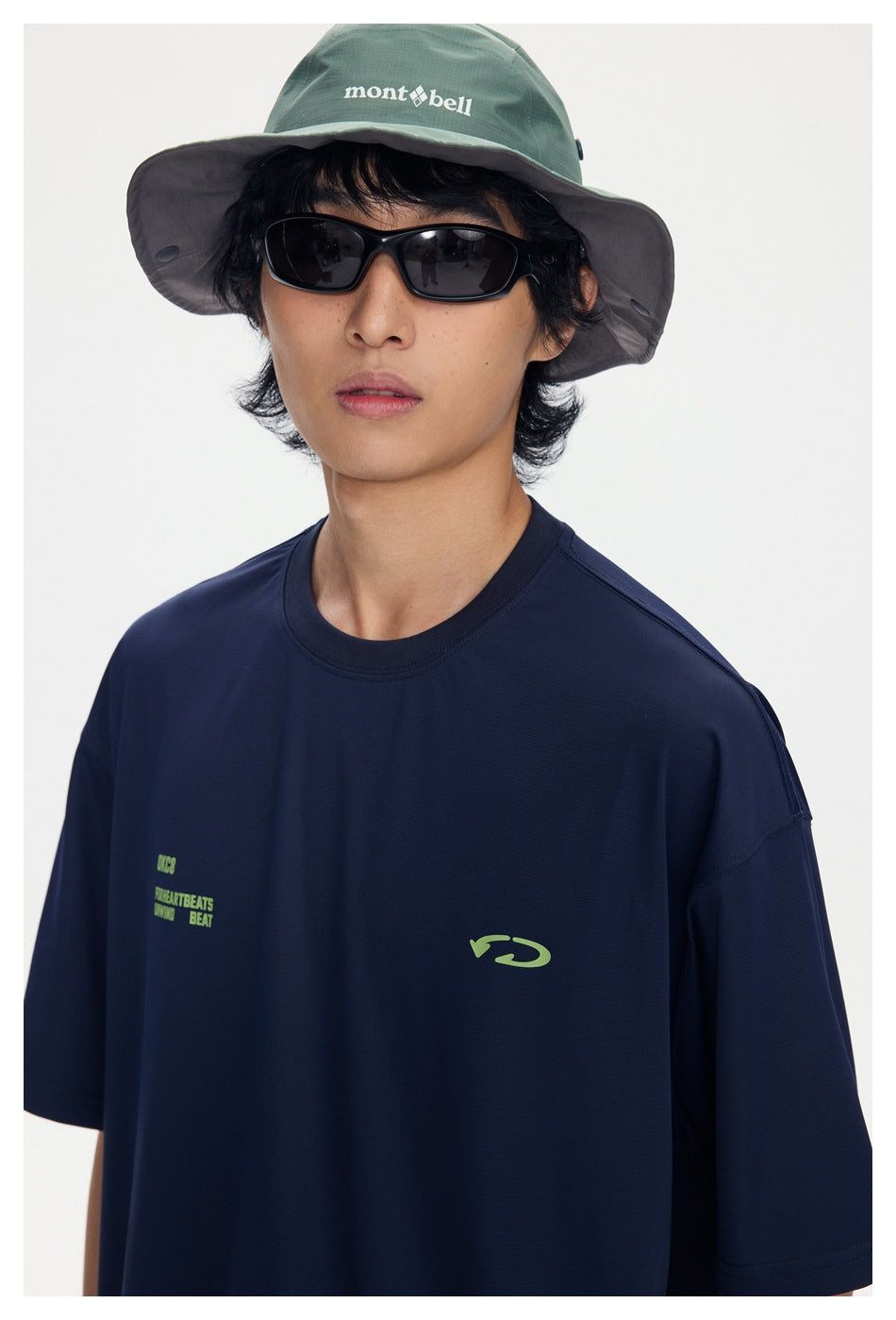 Close-up of a navy T-shirt with small lime chest graphics, worn by a model.