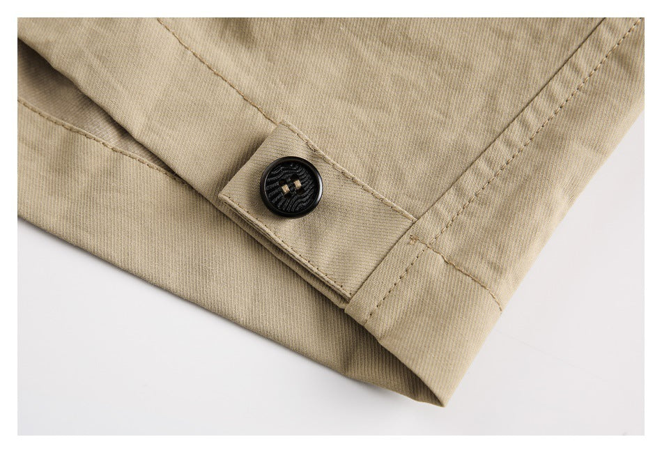 Close-up of a black button fastening a stitched tab on the tan pants cuff.