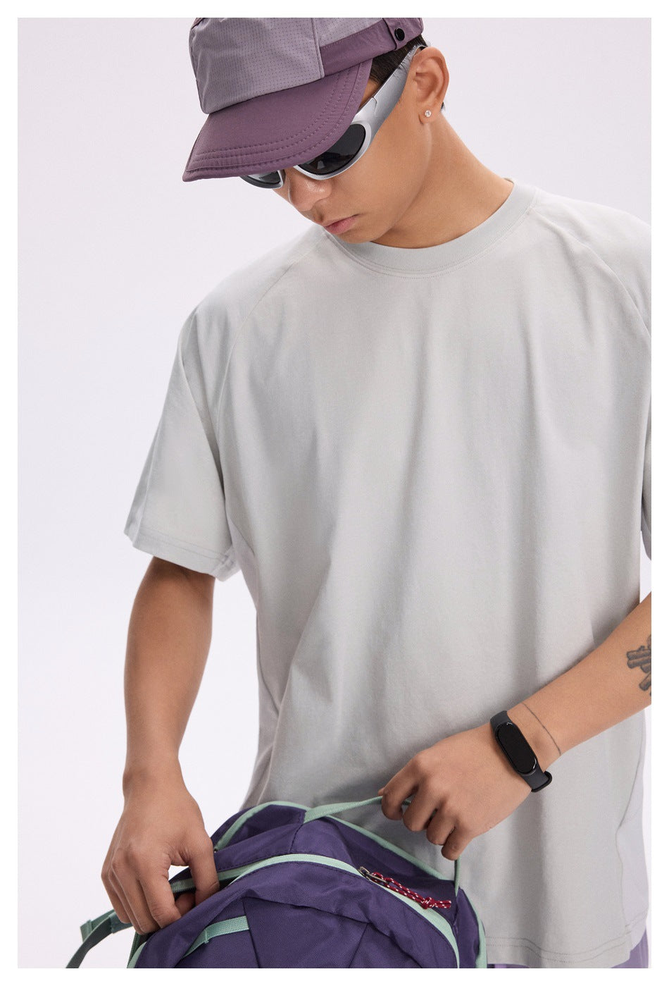 Close-up of a model wearing a light gray crew-neck T-shirt, showing its collar, sleeves, and relaxed fit.