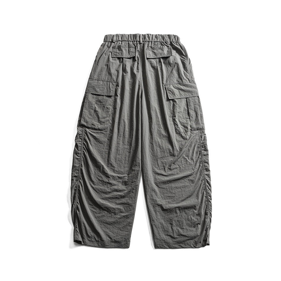 Back view of gray wide-leg cargo pants with an elastic waistband and multiple flap pockets, laid flat on white.