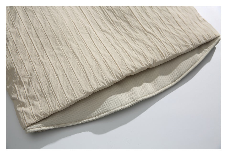 Close-up of the layered, crinkled cream garment hem with a ribbed inner edge.