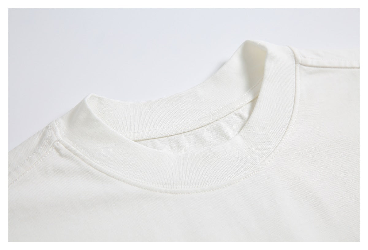 Close-up of the ribbed crew neckline and shoulder seam on an off-white T-shirt.