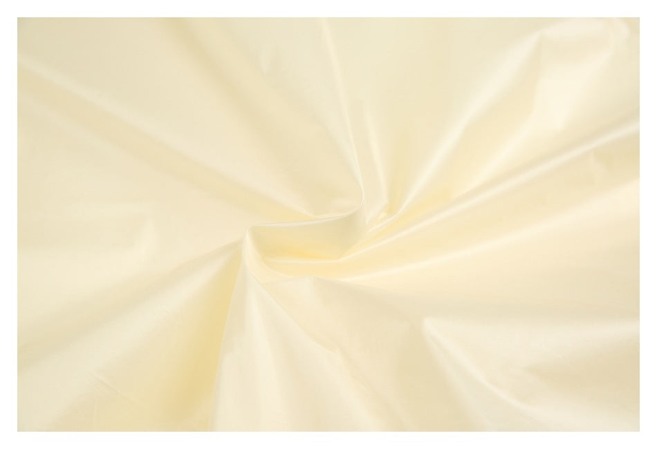 Close-up of smooth pale yellow fabric arranged in soft folds.