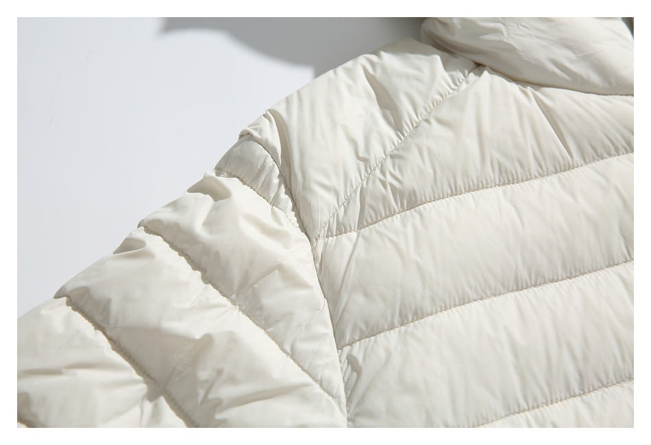 Close-up of an ivory padded jacket showing curved shoulder seams and horizontal quilted baffles.