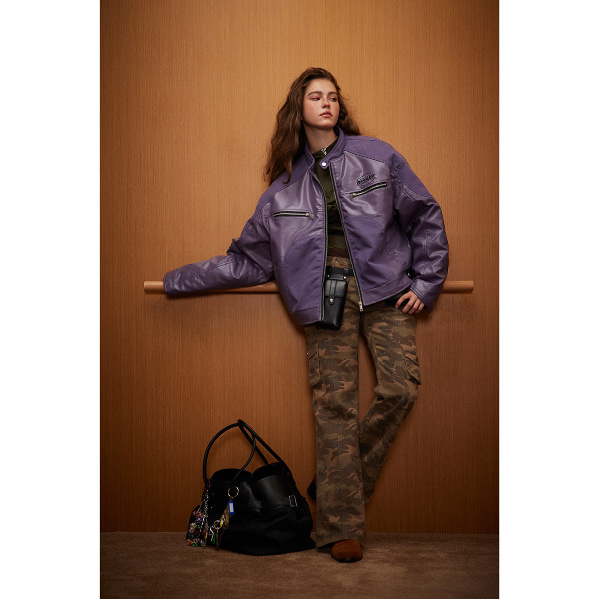 Model wearing a glossy purple zip-front jacket with chest pockets and camouflage trousers.