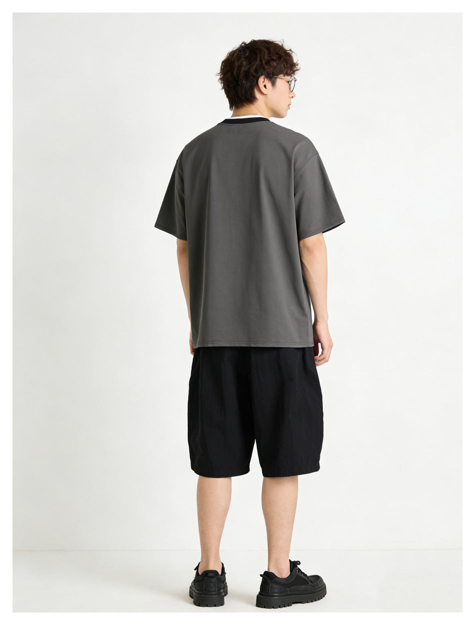 Back view of a model wearing a dark charcoal T-shirt with a contrasting collar and black shorts.