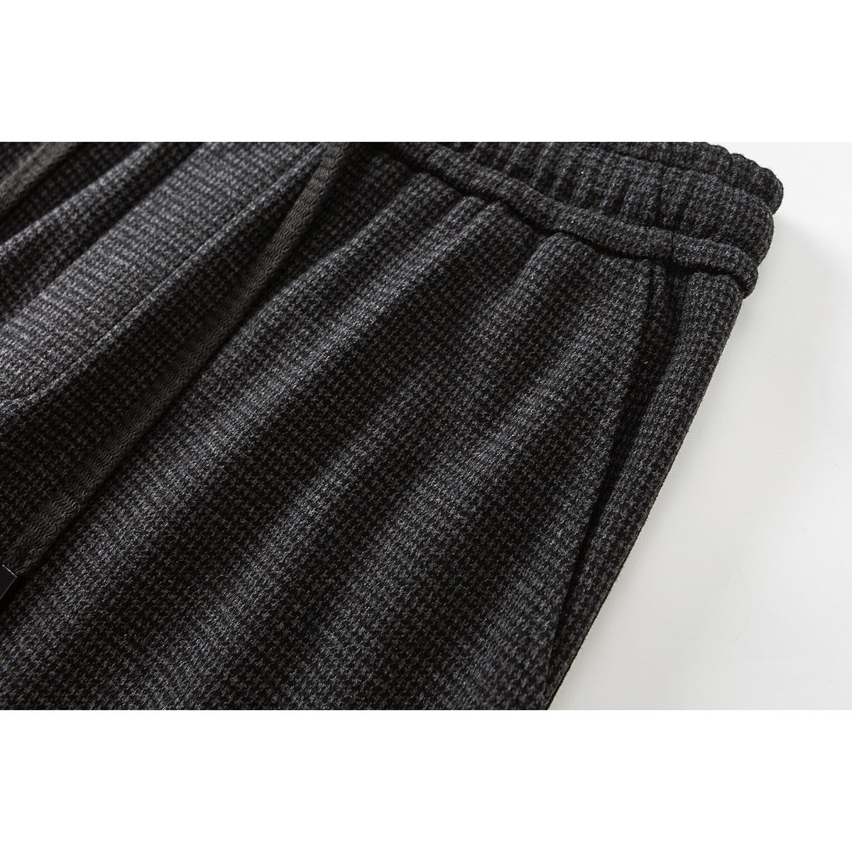 Close-up of charcoal gray patterned trousers showing the elastic waist and a pocket seam.