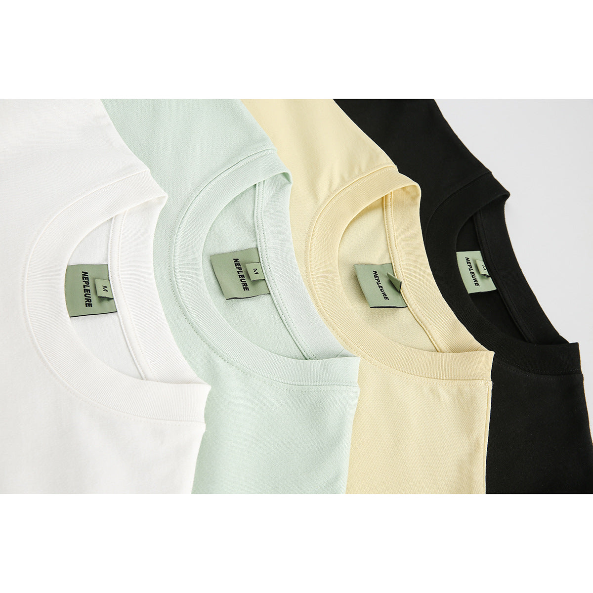 Close-up of four T-shirt collars in white, pale mint, pale yellow, and black, showing sewn-in neck labels.