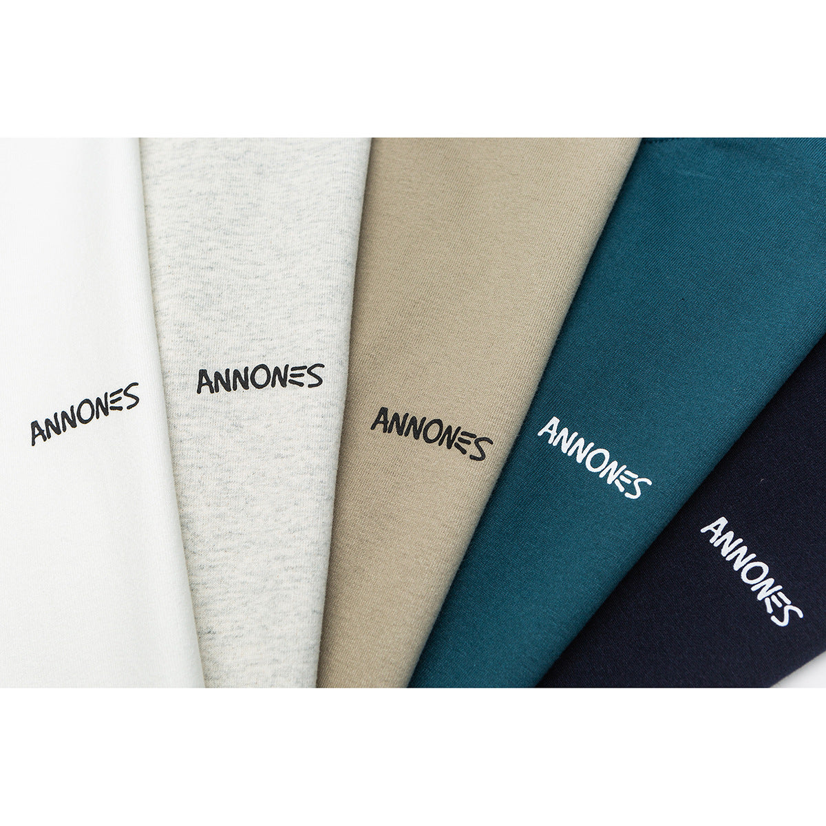 Close-up of five T-shirt colors—white, heather gray, tan, teal, and navy—with small ANN0NES lettering.