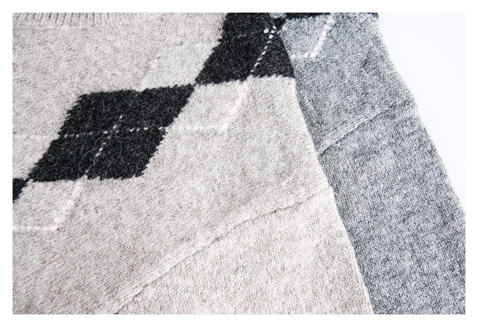 Close-up of a light beige and gray knit sweater with black argyle diamonds and a visible seam.