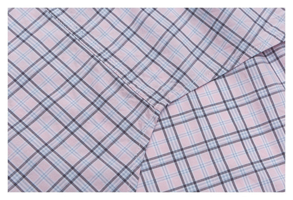 Close-up of a stitched seam on pale pink plaid shirt fabric.