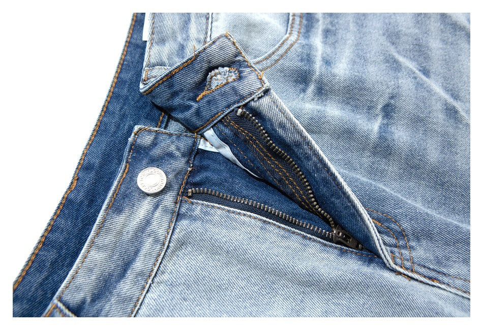 Close-up of the open zipper fly, metal button, and stitching on light-wash denim shorts.