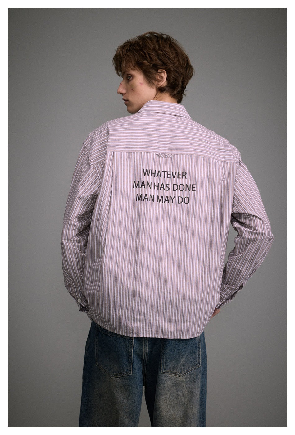 Back view of a model wearing a pink-and-white striped shirt with black text across the upper back.