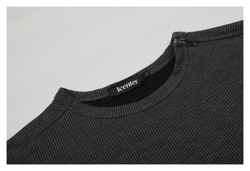 Close-up of a charcoal waffle-knit shirt neckline with a small zipper and sewn-in neck label.