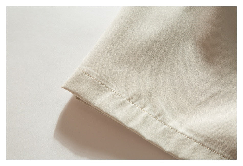 Close-up of the beige shorts' stitched hem.