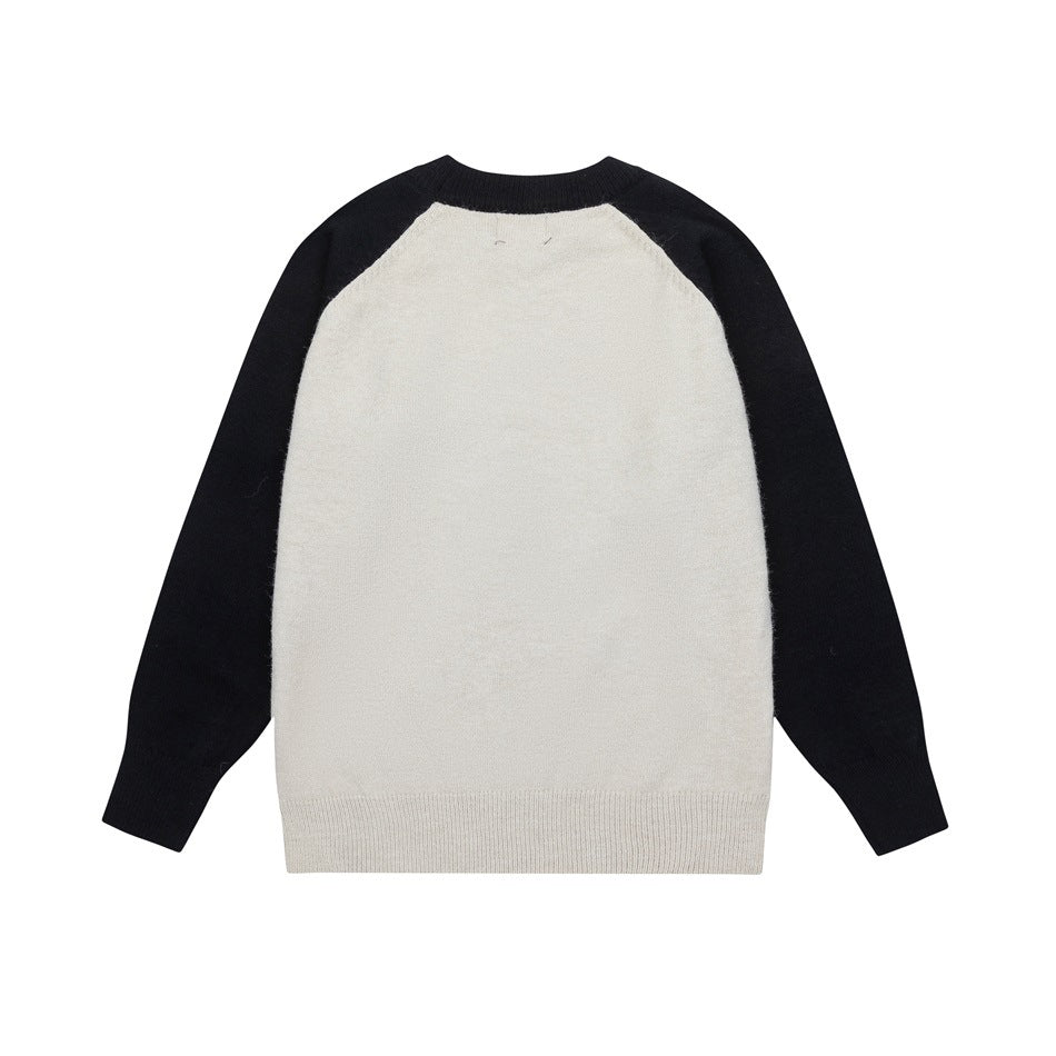 Back of a cream raglan sweater with black sleeves and ribbed neckline and hem, laid flat on a white background.