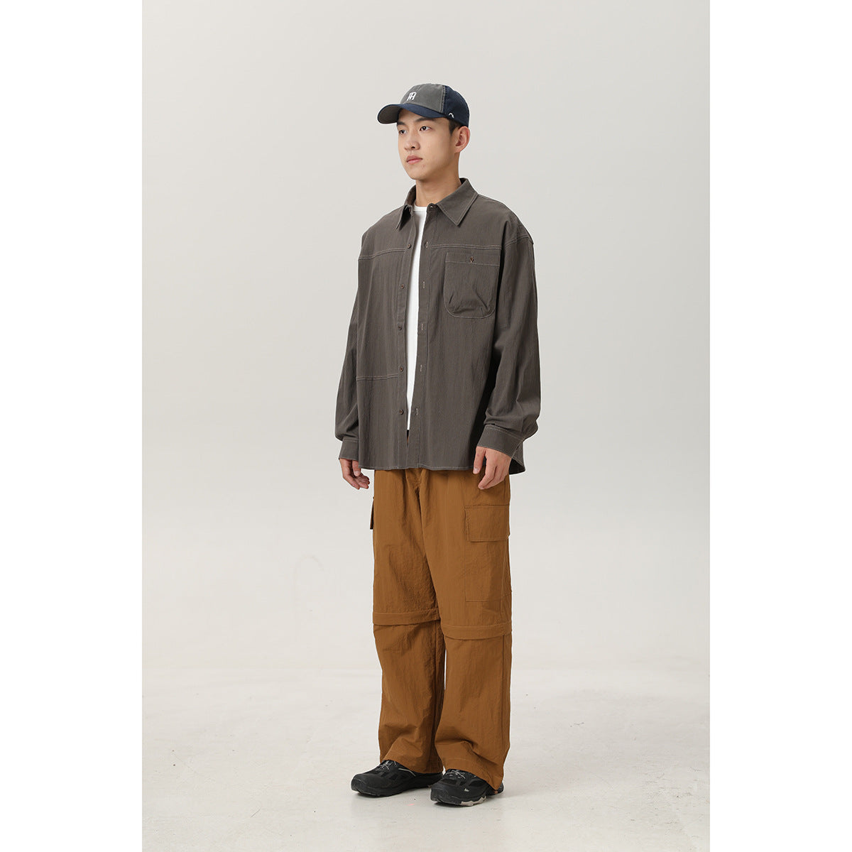 Full-length front view of a man wearing a charcoal gray button-up shirt with a chest pocket and brown cargo pants.