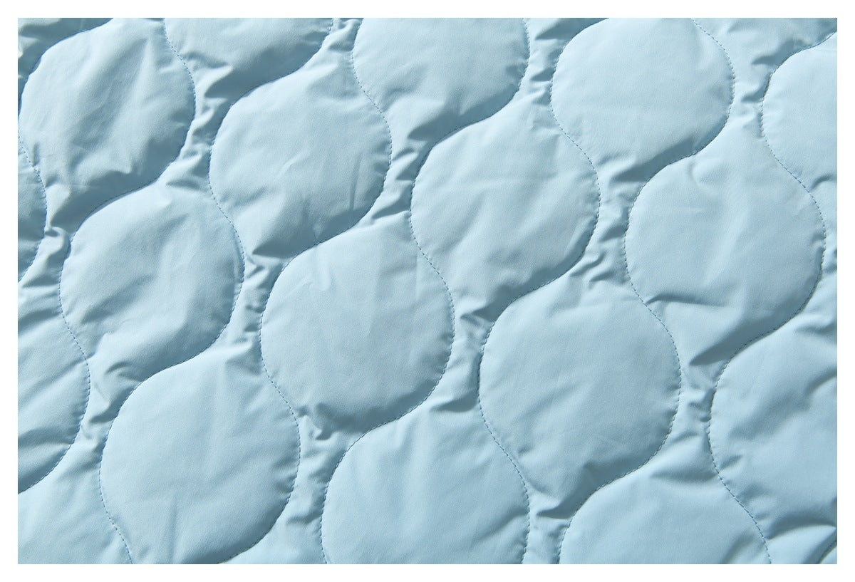 Close-up of pale blue quilted jacket fabric with repeating curved stitching.